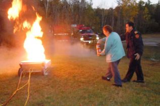Barbara Sproule of Ompah extinguishes a fire with North Frontenac fire chief Steve Riddell